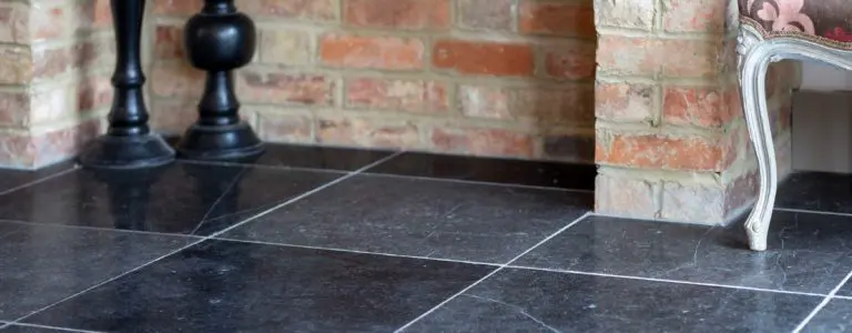 Black stone flooring interior, against red brick wall. Stone for trade and wholesale clients, including landscape gardeners. Natural Stone Consulting.